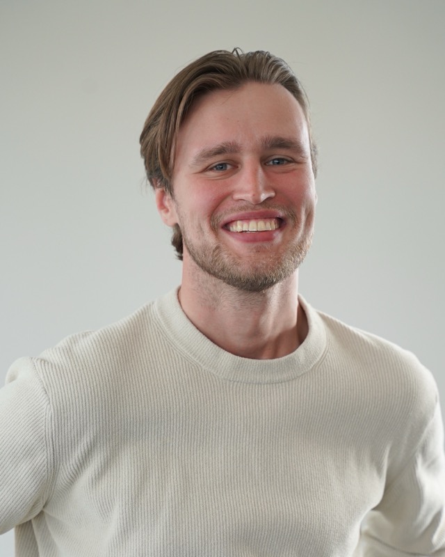 Portret van Aron van der Putten, half gedraaid, voor een lichte wand.